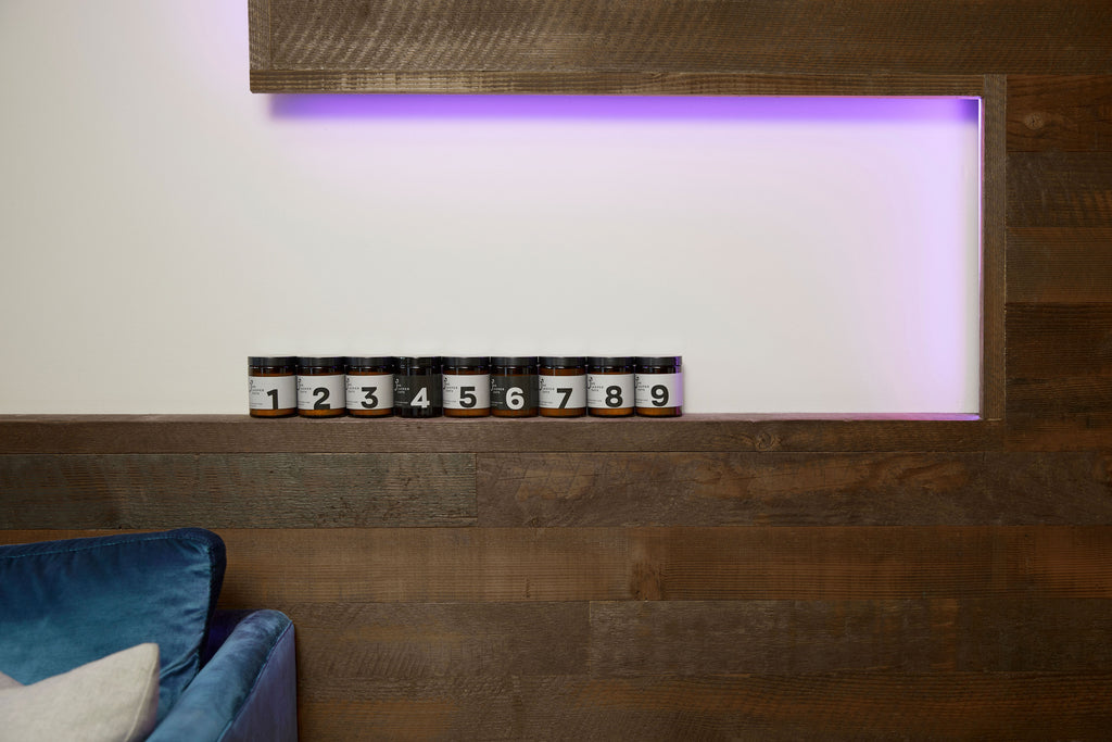 Medium candles 1 to 9 lined up on a wooden wall feature with purple light above it and a couch on the left